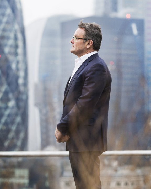 Wim Dejonghe in profile, with the City of London behind him